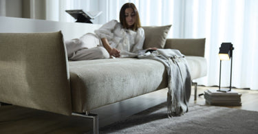 Udslået sovesofa med plaid, brugt som liggeplads i stuen